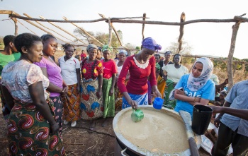 group of people standing around a freshly made cauldron of porridge