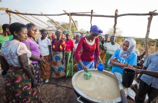 group of people standing around a freshly made cauldron of porridge