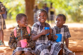 Image of three girls smiling with mugs.